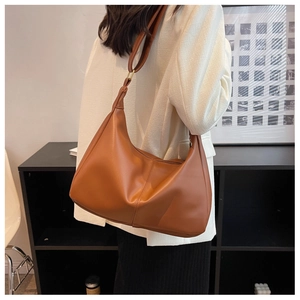 Detail view of large brown dumpling shoulder bag with thick strap and gold hardware