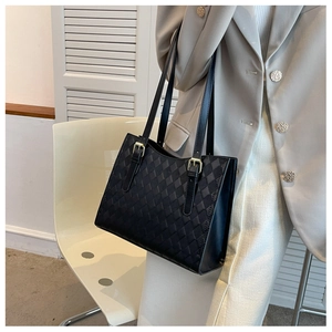 Close-up of black tote bag with checkered texture and gold adjustable shoulder buckle