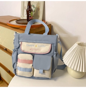 Detail of blue oxford tote bag with multi-color pockets and Happy & Lucky embroidery