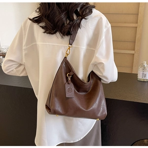 Detail of a vintage large dark brown hobo bag showing leather texture and gold hardware