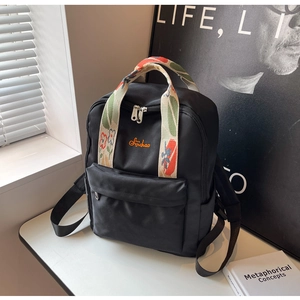 Détail du sac à dos en nylon noir avec poignée jacquard fleurie et logo Sichao orange