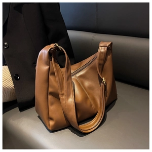 Detailed texture of brown retro faux leather shoulder bag on a dark leather sofa