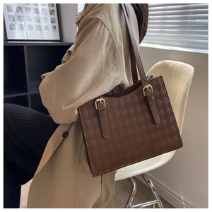 Detail of coffee brown quilted tote bag with metallic buckle on a slim shoulder strap