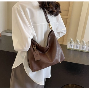 Detail of deep brown faux leather hobo bag with vintage gold hardware and a pebble texture