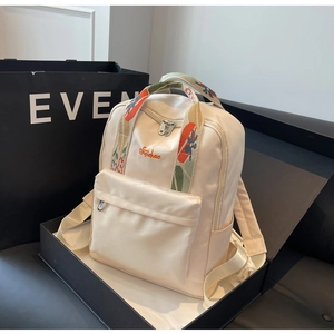 Détail du sac à dos en nylon crème avec poignée brodée ethnique et boîte cadeau