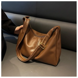 Detail of caramel leather shoulder bag with gold buckle on a gray leather background