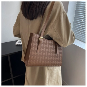 Detail of a brown quilted tote bag with diamond texture and double shoulder straps
