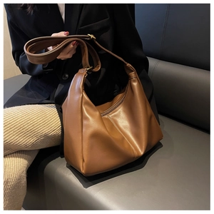 Detailed view of brown leather hobo bag with wide strap and soft textured pleats