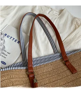 Detailed close-up of straw tote bag with brown leather handle and blue striped lining