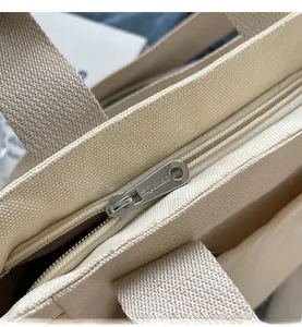 Macro detail of high-density canvas texture and smooth silver zipper on a beige tote bag