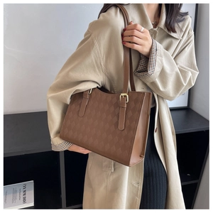 Detail of brown quilted tote bag with matte leather finish and golden adjustable buckle