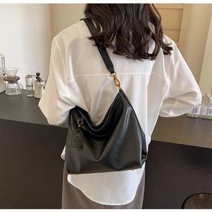 Close-up of black leather dumpling bag with gold hardware in a cafe setting
