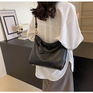Detail of soft black leather tote with adjustable strap and premium gold hardware accents
