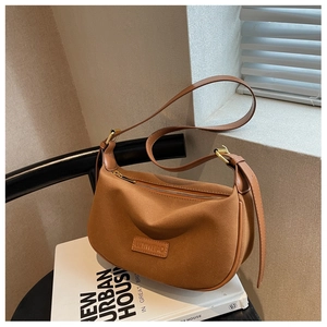 Detail shot of brown suede crescent bag texture and adjustable wide leather shoulder strap