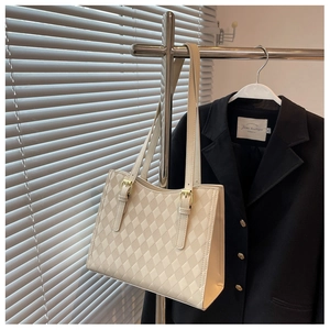 Close-up of beige quilted tote bag showing geometric texture and metal adjustment buckle