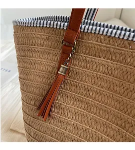 Detail of straw woven tote with brown leather tassel and blue striped lining