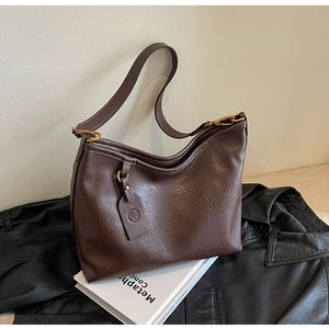 Detail of vintage brown leather hobo bag with smooth texture and golden metal buckle
