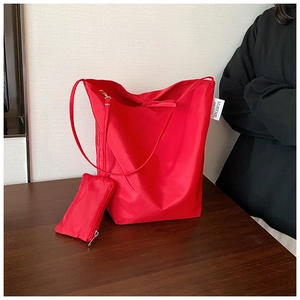 Dettaglio della borsa tote in oxford rosso con piccola pochette coordinata su un tavolo di legno