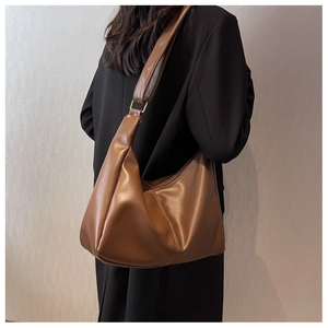 Detail of dark brown leather half-moon shoulder bag with golden metallic buckle