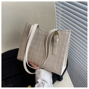 Detailed close-up of cream quilted tote bag with diamond pattern and adjustable metal buckle