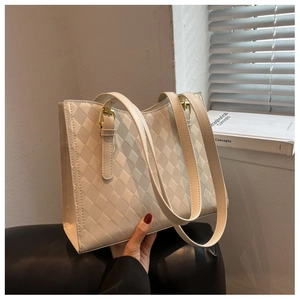 Close-up of cream quilted tote bag with diamond stitching and gold metal hardware