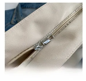 Detail of silver metal zipper and smooth beige canvas texture on minimalist tote bag