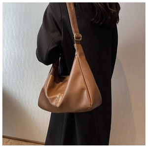 Detail of adjustable strap with gold buckle on brown leather hobo bag worn by model