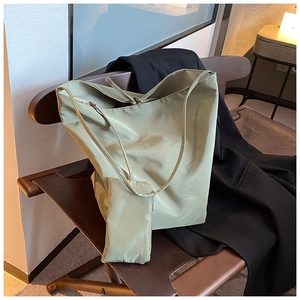 Dettaglio della borsa tote in nylon verde oliva con pochette abbinata su sedia in pelle