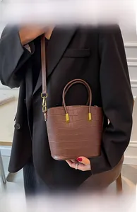 Detail of brown crocodile pattern bucket bag with gold hardware and shoulder strap