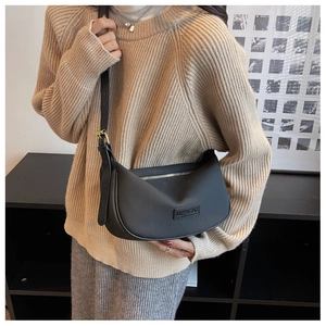 Model wearing black crescent shoulder bag with matte finish and adjustable strap