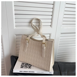 Close-up of beige quilted tote bag showing fine PU leather texture and gold metal buckles