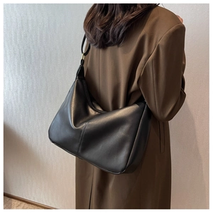 Detail of black soft leather dumpling bag with elegant gold metal ring strap connectors
