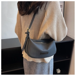 Close-up of black crescent shoulder bag featuring nylon texture and metallic buckle strap
