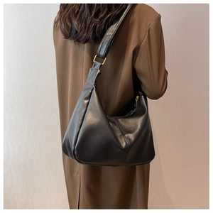Black hobo shoulder bag in soft PU leather with gold hardware worn with a brown trench coat
