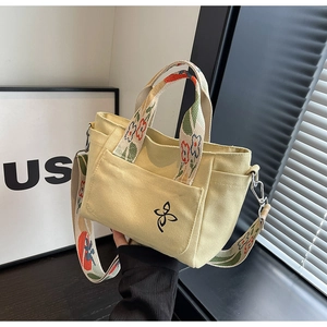 Detail of yellow canvas tote featuring floral embroidery and a wide ethnic strap