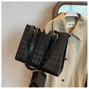 Close-up of black quilted tote bag with gold hardware and textured diamond pattern