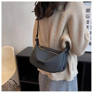 Detail of black crescent shoulder bag with leather logo tag and gold zipper on knit fabric