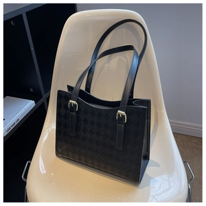 Detail of black quilted tote bag with gold hardware on a chair for high-end fashion look