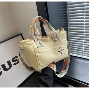 Detail of canvas tote bag featuring floral pattern strap and silver metal hardware hook