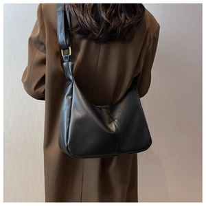 Close-up of black glossy leather Hobo shoulder bag with elegant gold metal ring buckles
