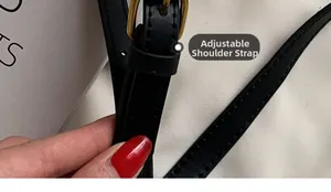 Close-up of black leather adjustable shoulder strap with vintage gold metal buckle