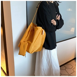 Dettaglio della borsa tote gialla in nylon con portamonete su modella donna