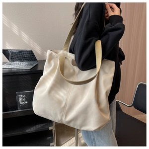 Detail of a cream canvas tote bag with brown straps in a professional commute setting