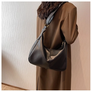 Minimalist black crescent bag styled with a brown coat, showcasing its large capacity