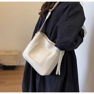 Detail of white leather bucket bag showing the fashion trend studio text and pocket