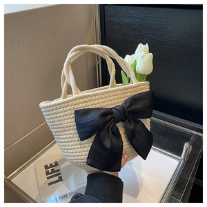Dettaglio borsa a secchiello in paglia intrecciata bianco crema con grande fiocco di raso