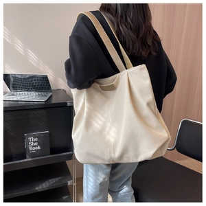 Spacious off-white canvas tote bag shown worn over the shoulder for a casual office look