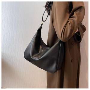 Model wearing a large black leather crescent bag with a soft glossy finish for autumn