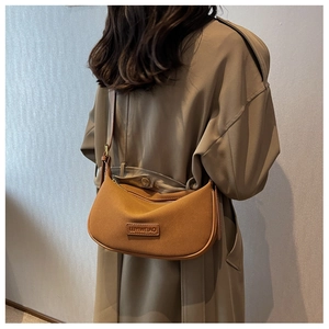 Brown suede half-moon shoulder bag styled with a khaki trench coat for a chic autumn look