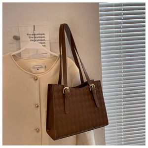 Detail of dark brown quilted tote bag showing diamond texture and gold metal buckle